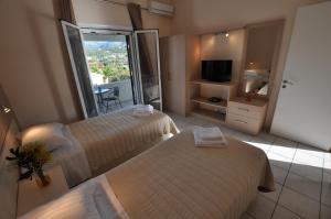 a hotel room with two beds and a balcony at Ammos in Roda
