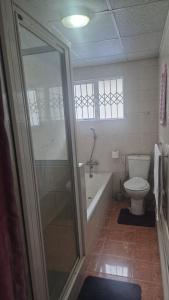 a bathroom with a tub and a toilet and a shower at Graceful Seniors in Durban