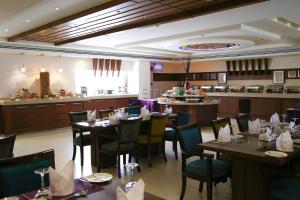 a restaurant with tables and chairs and a kitchen at Corniche Hotel Al Khobar in Al Khobar +38 photos