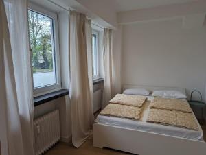 a white bedroom with a bed and two windows at HarmoNest 2 Mgladbach south in Mönchengladbach