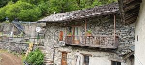 ein Steingebäude mit einem Balkon, auf dem Topfpflanzen stehen in der Unterkunft Lu Biulè Ca' d'Aldo in Groscavallo