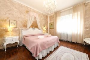 a bedroom with a pink bed and a chandelier at Le Bouganville Apartment- Downtown & close to the beach in Desenzano del Garda