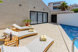 a patio with chairs and a swimming pool at VILLA STONE PEARL SUTIVAN - exceptional luxury new three-room villa - private pool and jacuzzi - perfect location right next to the town center and the beach - secured parking space in Sutivan