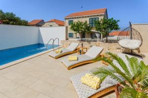 a patio with chairs and a swimming pool at VILLA STONE PEARL SUTIVAN - exceptional luxury new three-room villa - private pool and jacuzzi - perfect location right next to the town center and the beach - secured parking space in Sutivan