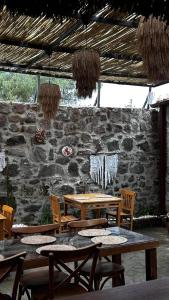a patio with tables and chairs and a stone wall at Chori Avlu Küçükköy in Ayvalık