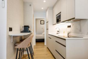 a kitchen with white cabinets and a sink and stool at Apartamentos Don Tomás in Jaén