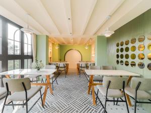 a dining room with tables and chairs and green walls at Little Charm Boutique Hotel in Hanoi