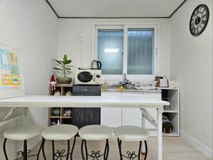 a kitchen with a white counter and stools in it at 행궁동-House2 in Suwon