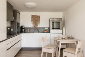 a kitchen with white cabinets and a table and chairs at Strandnest VILLA KAETHE am Kurpark - gemütliche 60qm Ferienwohnung für Zwei in Warnemünde