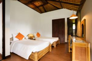 two beds in a room with white walls and wooden floors at The Buyan Resort Bedugul in Bedugul