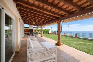 a patio with white chairs and a view of the ocean at Winahost Casa Nívar in Nívar
