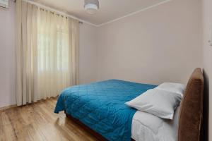 a bedroom with a bed with blue sheets and a window at Maslina Krtoli in Tivat