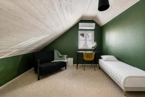 a bedroom with green walls and a bed and a chair at Wiedemanni Apartments in Haapsalu