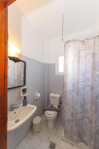 a bathroom with a sink toilet and a shower curtain at Lunar Seaside Hotel in Perissa +51 photos