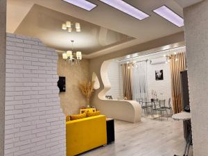 a living room with a yellow couch and a brick wall at Zarisha Home in Fergana