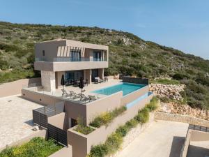a house with a swimming pool in front of a hill at Lina's Luxury Villas in Skala