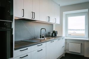 a kitchen with white cabinets and a sink and a window at Sea view apartment Haapsalu in Haapsalu