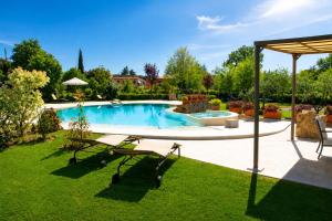 a swimming pool in a yard with chairs and an umbrella at Sant'Ippolito in Asciano