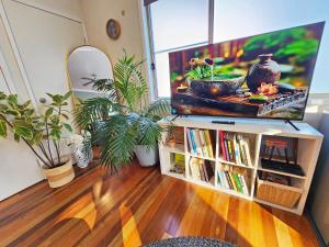 a living room with a tv on a stand with books at Cosy Studio with Forest Views, Noosa Hinterland in Doonan