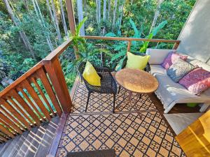 a balcony with a couch and a table and chairs at Cosy Studio with Forest Views, Noosa Hinterland in Doonan