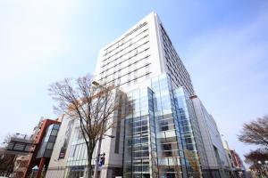 a tall glass building in a city at Richmond Hotel Aomori in Aomori