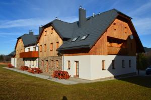 a large wooden building with a black roof at Apartmány Nova Lake in Nová Pec