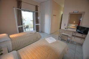 a hotel room with two beds and a desk and a television at Ammos in Roda