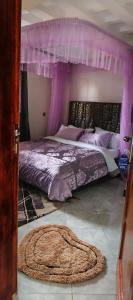 a purple bedroom with a bed with a canopy at Sylvan hotel in Kasangati