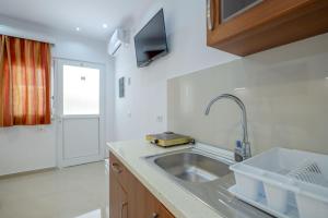 a kitchen with a sink and a tv on a counter at Ksamil Guesthouse Villa in Ksamil +86 photos