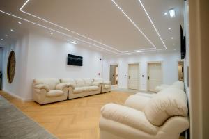 a living room with white couches and a tv at Leo Resort and Spa in Petrova