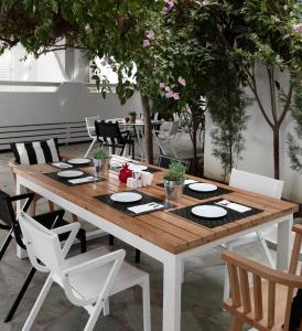 een houten tafel met witte stoelen eromheen bij Apollon Boutique Hotel in Parikia