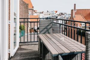a wooden bench on a balcony with a view at Divi Divi Zandvoort in Zandvoort
