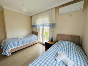 two beds in a room with a window at Evalacati - Villa Harnup- Detached house with private pool and garden in Alaçatı +59 photos