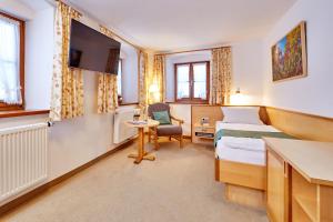 a hotel room with a bed and a desk and a chair at Gästehaus Enzianhof Hotel Garni in Oberammergau