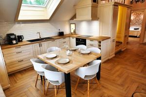 a kitchen with a wooden table and white chairs at La Suite Enchantée in Valentigney