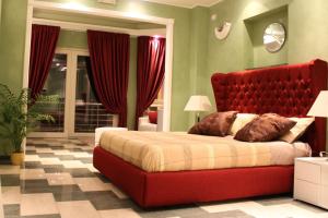 una camera con un grande letto rosso con testiera rossa di Central Rooms a Noto Marina