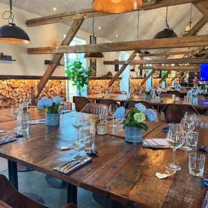 a large wooden table in a restaurant with wine glasses at Fun Art Blokhus in Blokhus