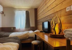 a room with two beds and a desk with a television at SappoLodge in Sapporo +16 photos