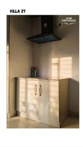 a kitchen with white cabinets and a black hood at Villa 27 in Sonāpur