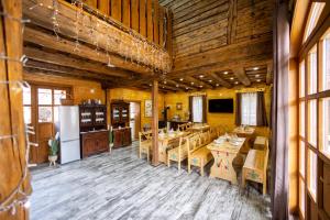 a restaurant with wooden floors and tables and windows at Székelyföld,Siklódi Kő Vendégház, Csűr in Şiclod