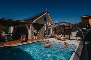 a group of people in a swimming pool at Vila Roháčka - Luxusná Vila so súkromným wellness a bazénom in Habovka