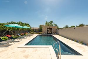a swimming pool with chairs and umbrellas on a patio at Villa Flora Zadar Villas in Perušić Benkovački