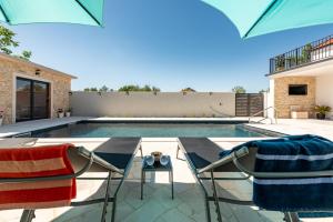 a swimming pool with two chairs and a table at Villa Flora Zadar Villas in Perušić Benkovački