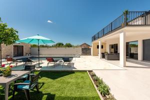 a patio with a table and chairs and an umbrella at Villa Flora Zadar Villas in Perušić Benkovački
