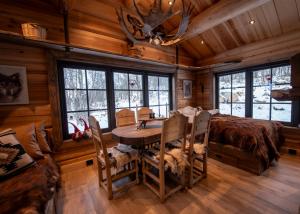 a dining room with a table and a bed and windows at Langedrag Naturpark in Tunhovd
