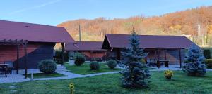 a log cabin with a tree in the yard at La Păstrăvărie ,,Casa Iov,, in Moroeni