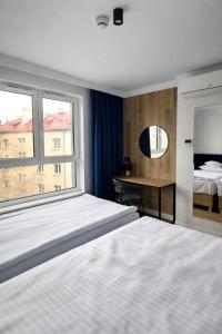 a bedroom with a bed and a desk and a window at Apartamenty Branicka in Białystok +53 photos