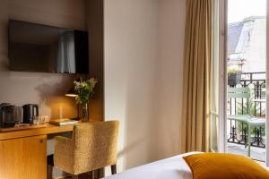 ein Hotelzimmer mit Bett, Schreibtisch und Fenster in der Unterkunft Hotel Le Six in Paris