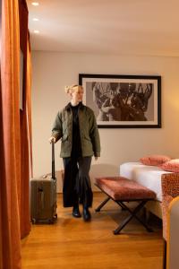 Ein Mann geht mit einem Koffer durch einen Raum. in der Unterkunft Hotel Le Six in Paris