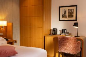 ein Hotelzimmer mit einem Bett, einem Schrank und einem Stuhl in der Unterkunft Hotel Le Six in Paris